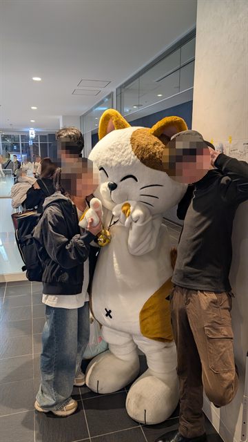 お店のマスコットの着ぐるみをはさんでポーズをとる参加者たち